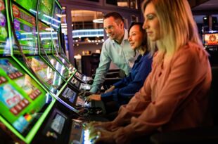 Zwei Frauen und ein Man spielen an Slot Machines.