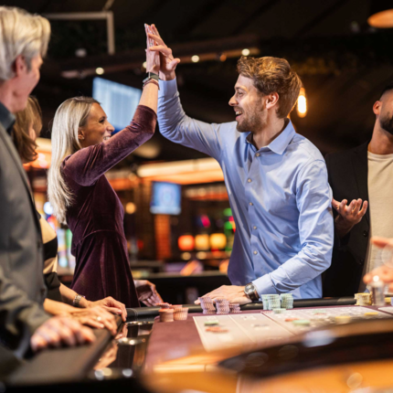 Zwei Personen freuen sich an einem Roulette-Tisch, während andere etwas unglücklich schauen.