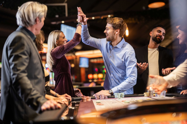 Zwei Personen freuen sich an einem Roulette-Tisch, während andere etwas unglücklich schauen.